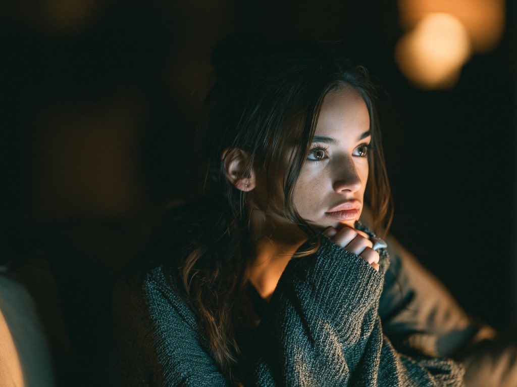 Person resting their chin on their hands in warm screen light